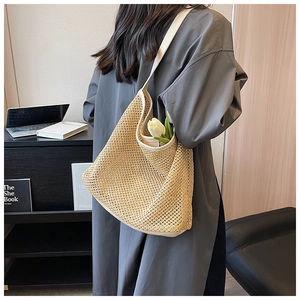 Detailed texture of woven straw beach bag with beige canvas trim and shoulder strap
