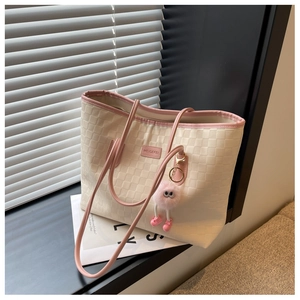 Detailed view of woven checkerboard tote bag with pink straps and plush charm