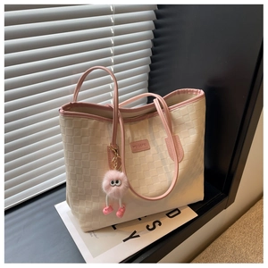 Detail of checkered tote bag with pink leather trim and fluffy monster charm