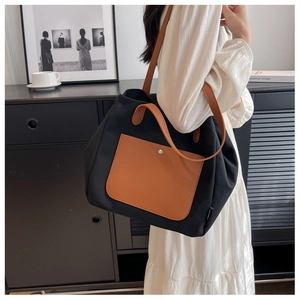 Detail of a large black canvas tote bag with brown leather pockets for daily commuting