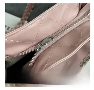 Detail of pink quilted leather bag featuring smooth silver zipper and woven handle