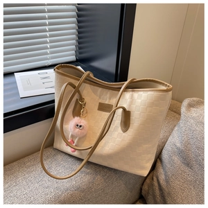 Detail of checkered texture on beige tote bag with leather straps and plush charm
