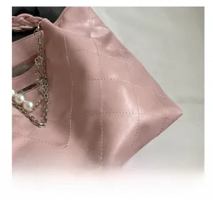 Detail of pink quilted leather tote with pearl charms and woven chain strap handles
