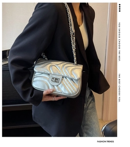 Silver metallic chain bag with wave stitching on model wearing a black blazer