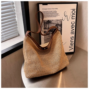 Detail of woven straw tote bag with brown leather handles and premium stitching texture