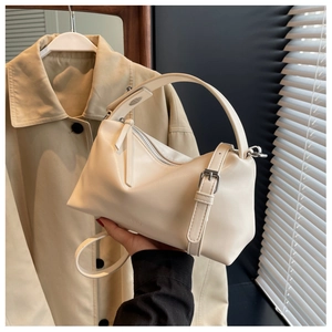 Detail view of cream leather boston bag with top handle and fine shoulder strap