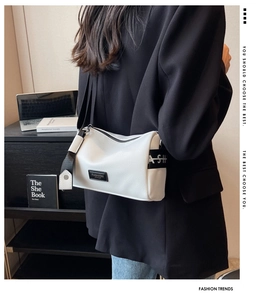 White litchi pattern leather pillow bag with wide lettered strap worn by model