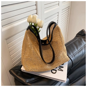 Close-up of woven straw tote bag with black leather straps in a bright lifestyle setting