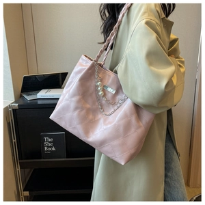 Pink quilted tote bag with woven handle and pearl flower chain shown on a model