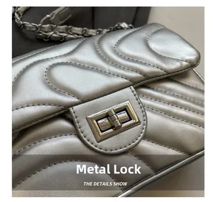 Detail of silver quilted crossbody bag featuring wave patterns and metallic turn-lock