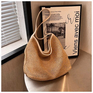 Detailed view of handmade woven straw shoulder bag with leather strap on table