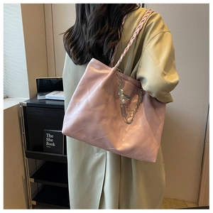 Detail of pink quilted tote bag with pearl chain charms and braided straps on shoulder