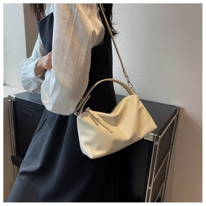 Close-up of cream soft PU leather handbag with elegant pleats and shoulder strap
