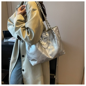 Detail view of silver quilted tote bag with pearl chain decoration on model shoulder