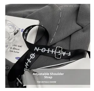 Détail de la large bandoulière réglable avec texte FASHION et boucle argentée sur sac blanc