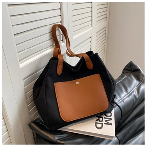 Detail of canvas tote bag showing brown leather pocket with metal button and black fabric
