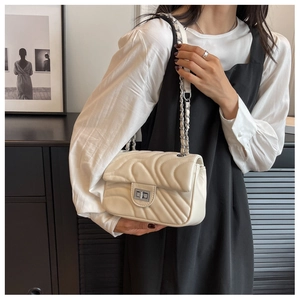 Detail of off-white quilted chain bag with silver twist lock and woven strap
