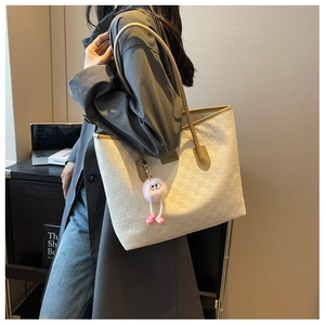 Detail of cream oversized tote bag with woven pattern and pink plush doll charm