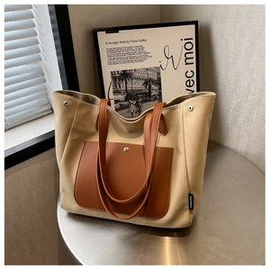 Detail of canvas tote bag showing the brown leather pocket with silver snap button