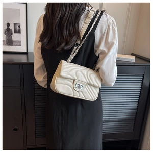 Detail of quilted leather shoulder bag with silver chain strap and metal turn-lock closure