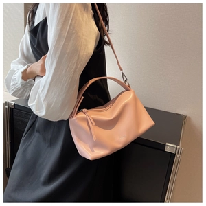 Pink faux leather pillow bag with dimple logo shown on model for casual shoulder carry