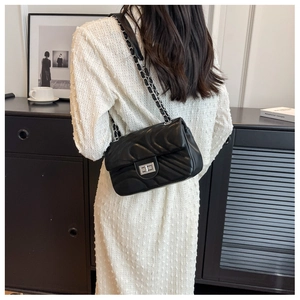 Detail of black quilted leather shoulder bag featuring silver chain strap and twist lock