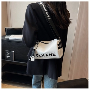 Detail of white textured crossbody bag with wide strap worn by a model in lifestyle setting