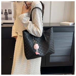 Close-up of the black and gray checkerboard tote bag with cute pink fuzzy charm