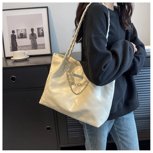 Detail of a large cream woven tote bag with silver chain, pearl charms and quilted texture
