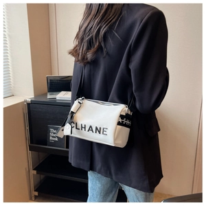 Close-up of white lychee grain leather pillow bag with stylish letter strap