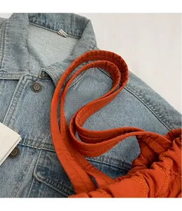Détail d'un sac cabas matelassé orange avec surpiqûres en losange sur veste en jean