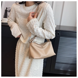 Chic beige matte leather shoulder bag styled with a textured white outfit in a modern room
