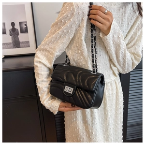 Detail of black quilted leather shoulder bag with silver chain and metal twist lock closure