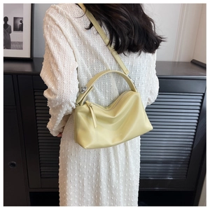 Detail of light yellow leather crossbody bag featuring a wide strap and top handle