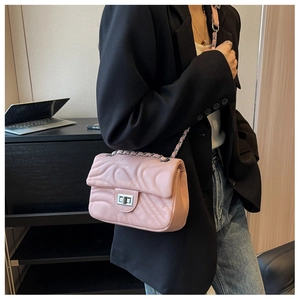 Detailed view of pink quilted leather crossbody bag with silver twist lock and chain strap