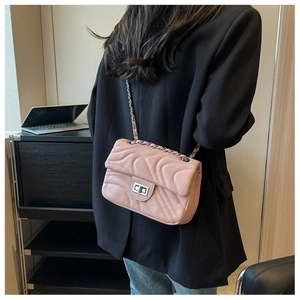 Detail view of pink quilted handbag with chain strap and metallic twist-lock closure