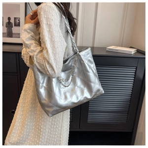 Detail of silver quilted tote bag featuring pearl metal chain and woven shoulder strap