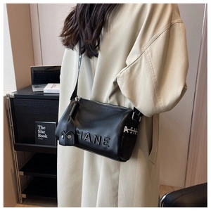 Detail of black textured leather cylinder bag with HANE embossing and wide strap
