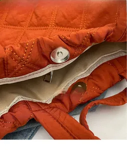 Détail du sac matelassé orange montrant son fermoir magnétique en métal brillant et doublure