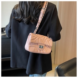 Detail of pink quilted flap shoulder bag featuring silver turn-lock and leather chain strap