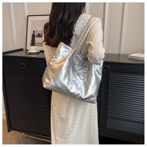 Detail of silver quilted tote bag with pearl chain and woven strap on a model