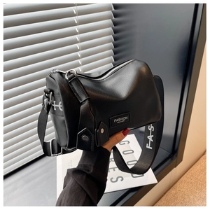 Detail of black pebbled leather cylinder bag featuring a wide logo strap and silver zipper