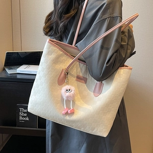Large capacity beige tote bag with pink straps and plush charm in a chic office setting