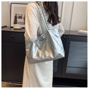 Detail of silver quilted tote bag with metallic finish and decorative pearl chain