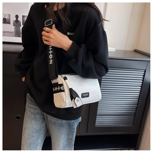 Detailed view of white pillow bag featuring a wide black strap with fashion lettering