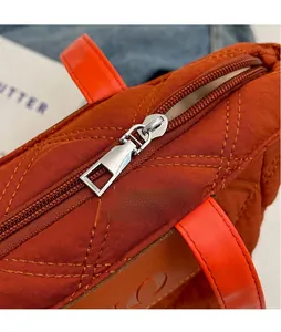 Detailed macro view of silver zipper and quilted orange fabric on tote bag