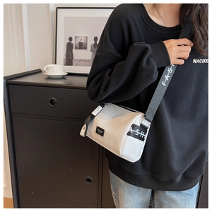 Gros plan d'un sac polochon blanc en cuir avec une large bandoulière noire à logo