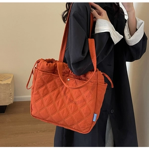 Detail of orange quilted tote bag with diamond stitching and side pocket drawstring