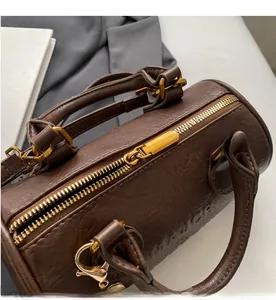 Close-up of a brown Boston bag showing a smooth metal zipper and textured leather