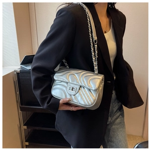 Detail of silver wavy quilted texture and metallic chain strap on a chic shoulder bag